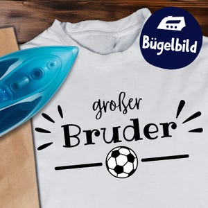 Peut inclure: T-shirt blanc avec l'inscription "großer Bruder" et un ballon de football. Un fer à repasser bleu est visible à gauche. Un cercle bleu foncé avec le texte "Bügelbild" est en haut à droite.