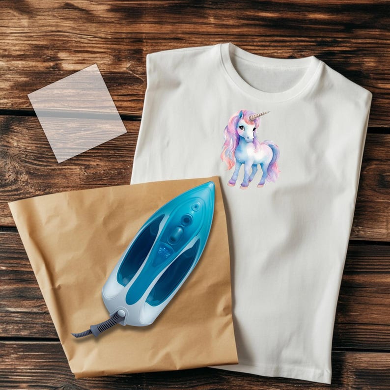 May include: White t-shirt with a watercolor unicorn design, a blue and white iron, and a brown paper sheet. The iron is approximately 12 inches long. The unicorn has a pink and purple mane and tail.