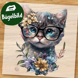 Könnte beinhalten: Ein Bügelbild mit einem grauen Kätzchen mit großen blauen Augen und einer schwarz umrandeten Brille. Das Kätzchen ist mit hellen Blumen an den Ohren und einem bunten Strauß aus blauen, violetten und gelben Blumen an der Basis verziert.