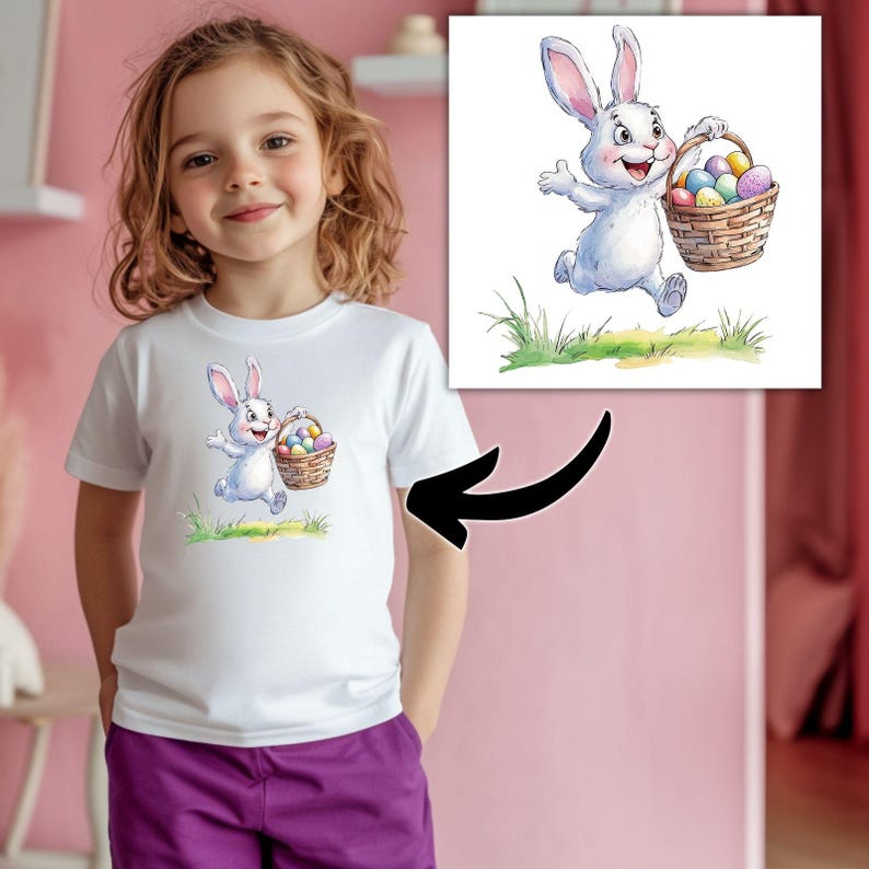 K&ouml;nnte beinhalten: Wei&szlig;es T-Shirt mit einem Cartoon-Bild eines wei&szlig;en Kaninchens, das einen Korb mit bunten Ostereiern h&auml;lt.