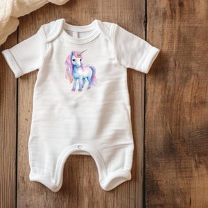 May include: White baby onesie with a watercolor unicorn design. The unicorn has a pink and blue mane and tail, a silver horn, and is standing on all fours. The onesie has short sleeves and a snap closure.