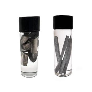 May include: Two clear glass vials with black screw-on caps. The left vial contains several small, irregular, dark gray metallic chunks submerged in clear liquid. The right vial contains several long, thin, dark gray metallic rods in clear liquid.