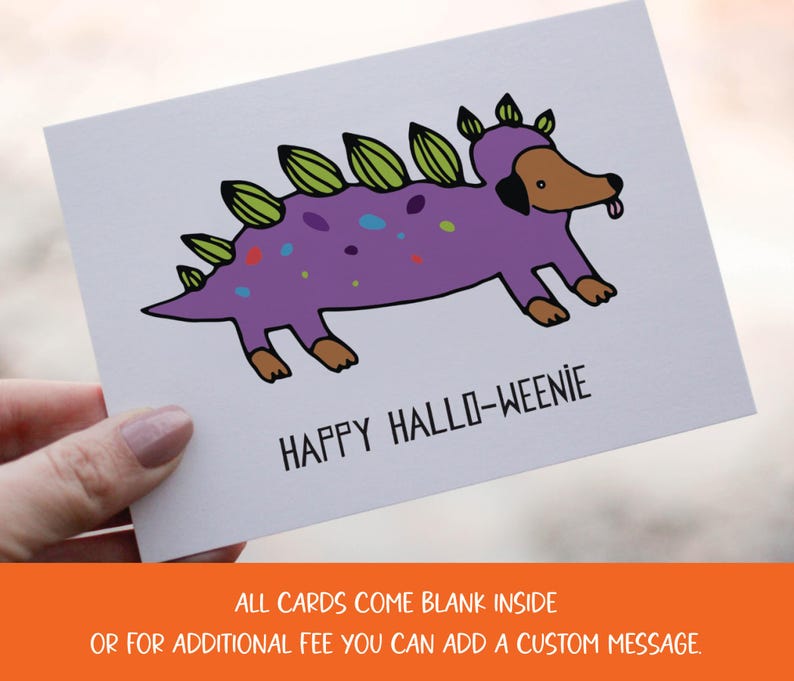 A cute and funny illustration of a dachshund dog wearing a dinosaur costume with the words happy halloweenie. Perfect greeting card for halloween and dog lovers.