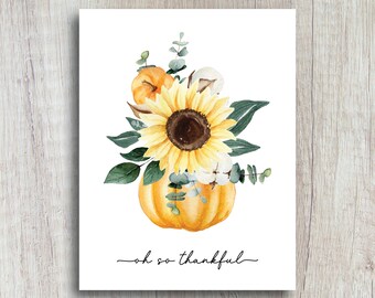 Puede incluir: Ilustración en acuarela de un girasol, calabazas y vegetación dispuestas en un jarrón con forma de calabaza. La imagen presenta un girasol amarillo brillante, calabazas naranjas y hojas verdes. Las palabras "oh so thankful" están escritas en cursiva.