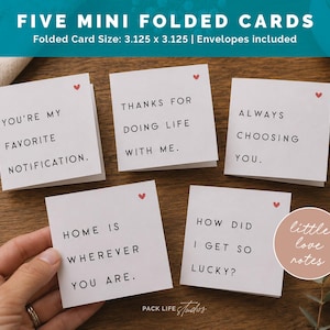 May include: Five square white folded cards with black sans-serif text and a small red heart icon. The cards feature phrases: You're my favorite notification, Thanks for doing life with me, Always choosing you, Home is wherever you are, How did I get so lucky? Size 3.125 x 3.125 inches.