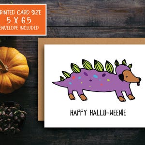 A cute and funny illustration of a dachshund dog wearing a dinosaur costume with the words happy halloweenie. Perfect greeting card for halloween and dog lovers.