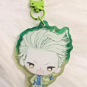 May include: A green and white anime-style keychain featuring a character with light green hair and a blue and green outfit. The keychain has a green clasp and a green border.