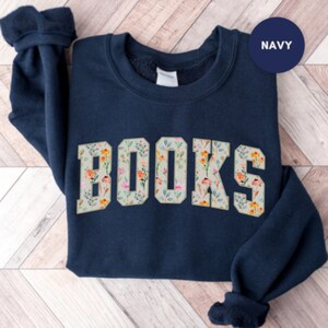 Pu&ograve; includere: Felpa blu navy con un design a stampa floreale che compone la parola "LIBRI" in lettere bianche.