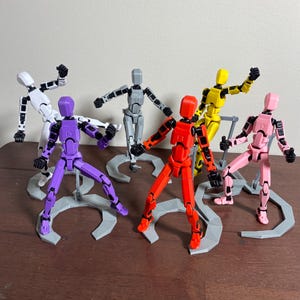 Puede incluir: Una colección de figuras de acción articuladas en varios colores, incluyendo blanco, morado, gris, rojo, amarillo y rosa. Cada figura está posada sobre un soporte gris, mostrando su diseño flexible. Las figuras están diseñadas para ser posadas en varias posiciones.