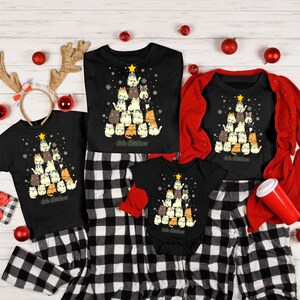 May include: A family matching Christmas pajama set with a black and white plaid pattern. The pajamas feature a black t-shirt with a Christmas tree design made of cats. The text "Cat Christmas" is printed on the shirt.