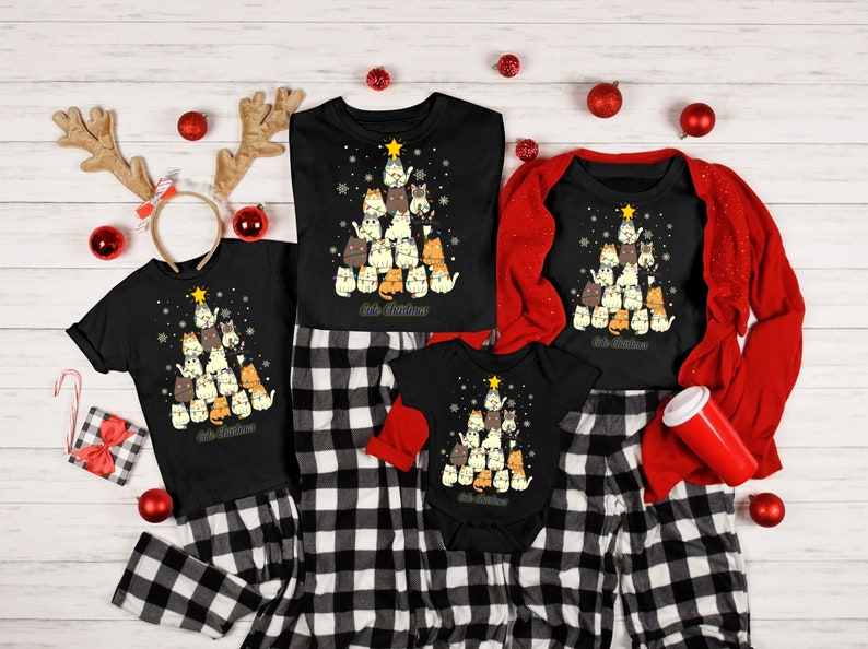 May include: A family matching Christmas pajama set with a black and white plaid pattern. The pajamas feature a black t-shirt with a Christmas tree design made of cats. The text "Cat Christmas" is printed on the shirt.