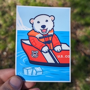 May include: A white polar bear wearing a red life jacket and a blue and white lifeboat with the text "U.S. CO" on the side. The bear is smiling and holding onto the lifeboat. The lifeboat is floating in blue water with two ice cubes in the foreground.