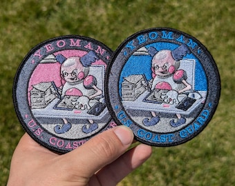 May include: Two embroidered patches featuring a cartoon character with glasses and a pink and blue background. The text on the patches reads "Yeoman, US Coast Guard".