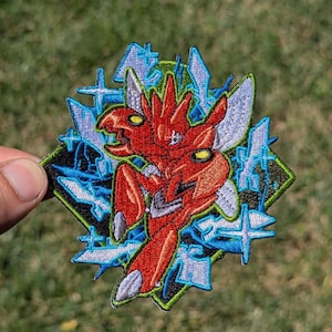 May include: An embroidered patch featuring a red, insect-like creature with sharp claws and yellow eyes. The design is set against a black diamond background with bright blue, star-shaped energy bursts and light blue wing-like accents throughout.