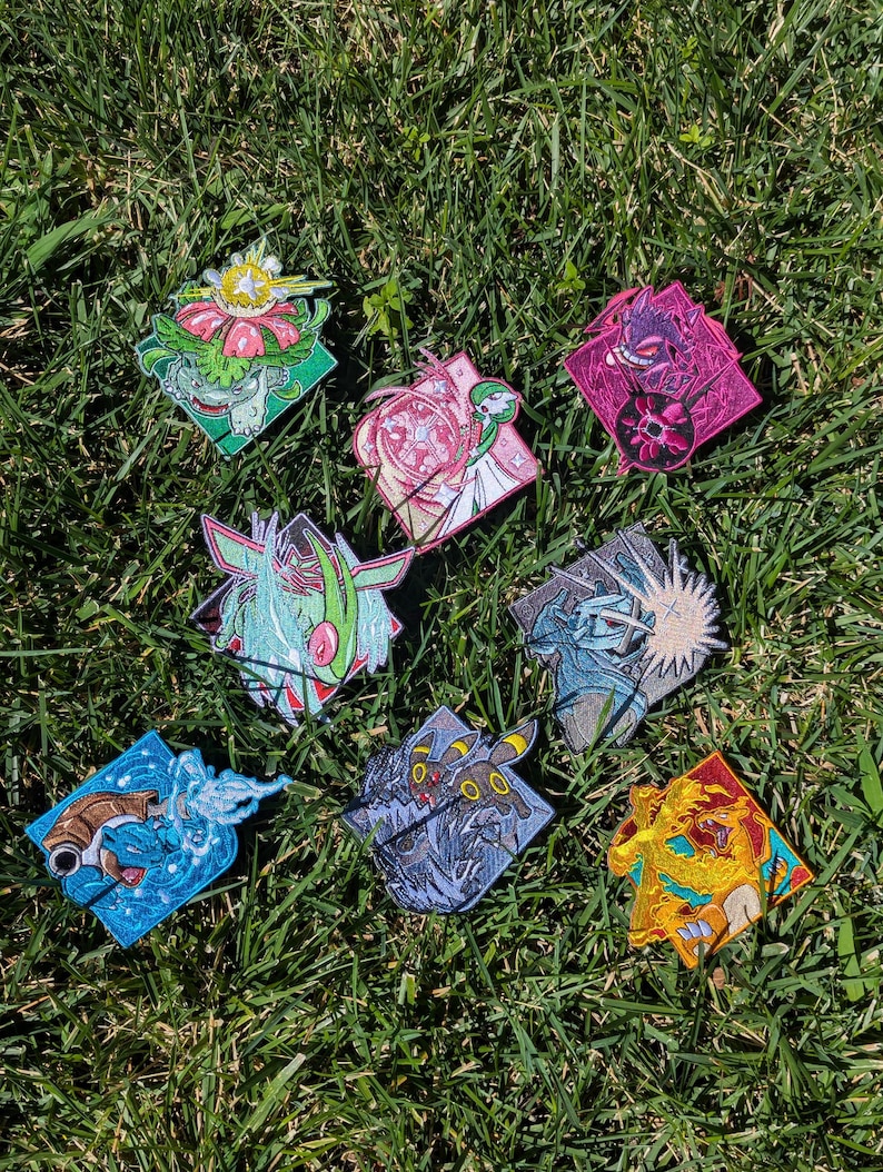Op de afbeelding: Een verzameling van acht vierkante geborduurde patches met diverse kleurrijke wezens met dynamische actie-effecten, waaronder een groen plantwezen, een roze psychisch figuur, een paarse geest, een blauwe waterschildpad en een gele vuurdraak.