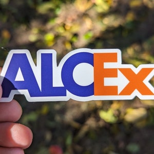 May include: A blue and orange sticker with the word "ALCEX" printed on it.
