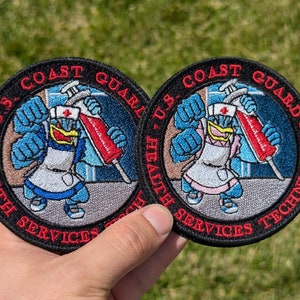 May include: Two embroidered patches featuring a cartoon bird wearing a nurse's uniform and holding a syringe. The patches are black with red and white text that reads "U.S. Coast Guard Health Services Technician".