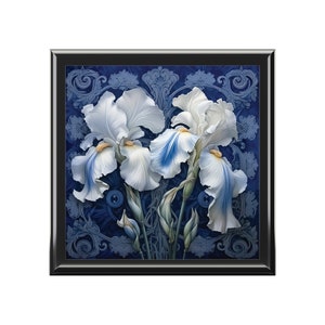 May include: A framed painting of three white irises with blue accents against a dark blue background with a decorative pattern.