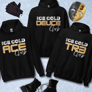 May include: Black hoodies with the text "ICE COLD ACE Club", "ICE COLD DEUCE Club", and "ICE COLD TRE Club" in white and gold lettering. The image also includes black gloves, a gold and black mask, and black boots.