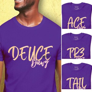 May include: Purple t-shirts with gold and white text. One shirt reads "DEUCE Dawg", another "ACE Dawg", a third "TR3 Dawg", and the last "TAIL Dawg". The shirts are short-sleeved and have a crew neck.