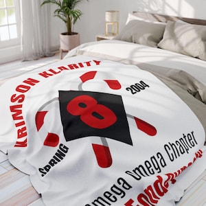 May include: White blanket with a large red number 8 on a black square, surrounded by red and white accents. The blanket has text that reads "KRIMSON KLARITY", "SPRING", "2004", and "Omega Omega Chapter".