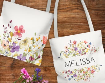 May include: Two white canvas tote bags with floral designs and the name "Melissa" printed on one of the bags. The bags have white straps.