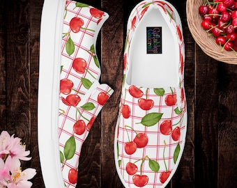 May include: White slip-on shoes with a cherry pattern. The design features red cherries and green leaves on a white background with a red grid pattern. The shoes have white soles and the text "Giftables Galore!!" is visible inside one shoe.