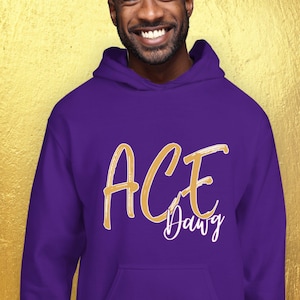 Puede incluir: Una sudadera con capucha morada con el texto "ACE Dawg" en escritura dorada. La sudadera con capucha tiene una capucha con cord&oacute;n y un bolsillo delantero. La persona de la imagen est&aacute; sonriendo.