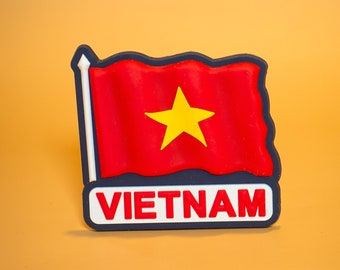May include: A red and yellow flag with a yellow star on a blue background. The flag is attached to a white pole and has the word "VIETNAM" written below it.