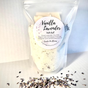 May include: A white resealable bag filled with a white bath soak with dried lavender flowers. The label reads "Vanilla Lavender Milk Bath" and lists the ingredients: Dried Lavender, Dry Milk, Epsom Salt, Himalayan Pink Salt, Lavender and Vanilla Essential Oils. The label also includes the text "Sweetie Pie Blooms" and the website address "sweetiepieblooms.etsy.com".