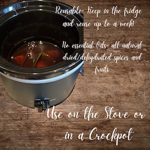 May include: A black slow cooker with a dark liquid inside, containing spices and fruits. Text on the image reads: "Reusable - keep in the fridge and reuse up to a week!" and "Use on the Stove or in a Crockpot."