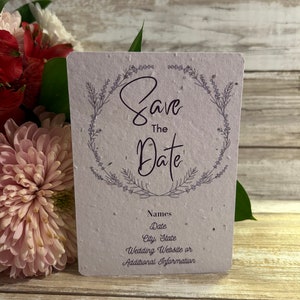 May include: A white save the date card with a purple floral wreath and the text "Save the Date" in purple script. The card also includes the text "Names, Date, City, State, Wedding Website or Additional Information".