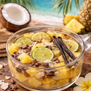 May include: A clear glass bowl filled with pineapple chunks, lime slices, and vanilla beans. The bowl sits on a wooden surface, with a coconut half and pineapple in the background. The scene evokes a tropical theme.