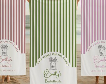 May include: Three beach towels with vertical stripes in burgundy, green, and lavender. Each towel has a white banner with the text "Last Toast on the Coast" and "Emily's Bachelorette Miami Florida Beach."