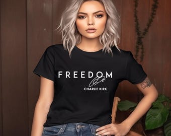 May include: Black crew neck t-shirt with the word "FREEDOM" in white capital letters and a signature below it. The shirt is made of a soft material.