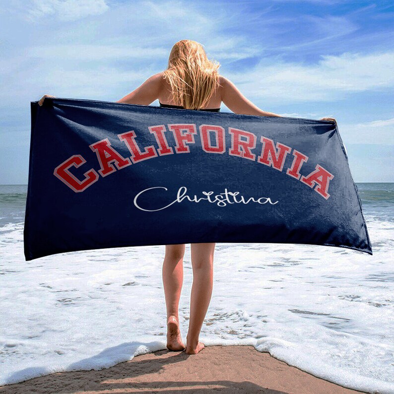 May include: A blue beach towel with the text "CALIFORNIA" in red and white lettering. The name "Christina" is written in cursive below the text.