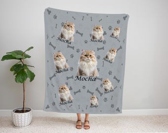 May include: A light gray blanket featuring multiple images of a fluffy cat with the name "Mocha" printed in black. The blanket also has paw prints and bone shapes scattered across the surface.