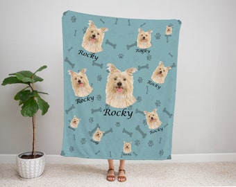 May include: A soft blue fleece blanket with a repeating pattern of a dog's face, bone shapes, and paw prints. The dog's name, "Rocky", is printed on the blanket.
