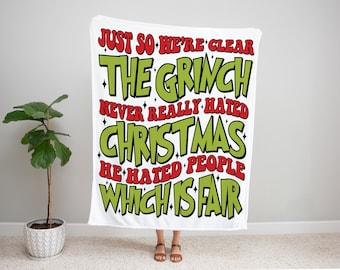 May include: White throw blanket with green and red text that reads "Just so we're clear, The Grinch never really hated Christmas, he hated people, which is fair."