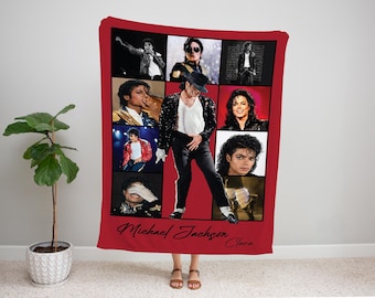 May include: A red rectangular fleece blanket featuring a photo collage of Michael Jackson in various performance outfits and poses. The center shows a large image of the artist in a black jacket and white shirt. The text Michael Jackson Clara is printed.
