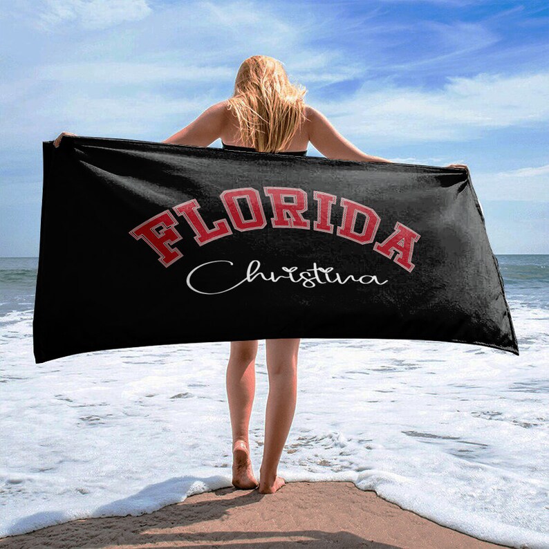 May include: Black beach towel with red text that says "FLORIDA" in a collegiate font. The name "Christina" is written in cursive below the state name.