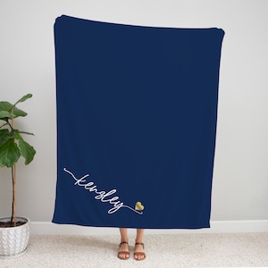 May include: A navy blue fleece blanket with the name "Kingsley" written in white cursive script and a gold heart.