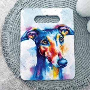 May include: A rectangular chopping board with a handle cutout featuring a vibrant watercolour painting of a dog. The canine portrait displays a mix of deep blue, bright yellow, and warm red tones against a light, splattered background.
