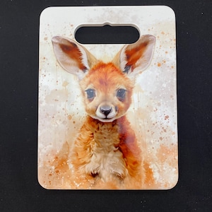 May include: A white rectangular decorative item with a top cutout, showcasing a watercolour illustration of a baby kangaroo. The kangaroo has reddish-brown fur and large ears, set against a backdrop of beige and brown paint splatters.