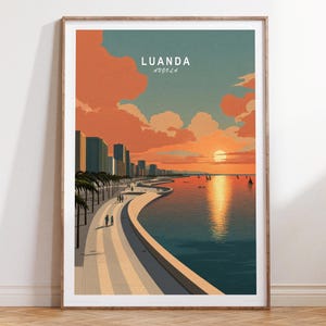 May include: A framed art print featuring a coastal scene of Luanda, Angola, at sunset. The artwork depicts a waterfront promenade, palm trees, buildings, and sailboats on the water, under a sky of orange and blue hues. Text at the top reads "Luanda Angola."
