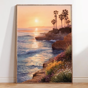 May include: A framed watercolour painting of a coastal sunset. The artwork depicts a vibrant orange and yellow sky, with palm trees silhouetted against the setting sun. The ocean waves crash against the rocky shore, with colourful wildflowers in the foreground.