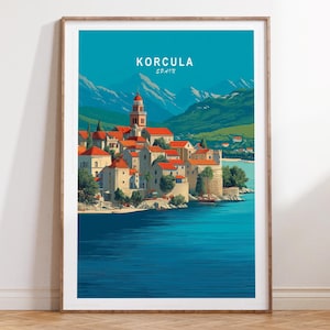 May include: A framed art print featuring a coastal town scene. The artwork depicts buildings with red tile roofs, a tall bell tower, and a blue sea. The text "KORCULA SPAIN" is at the top of the print. Mountains are visible in the background.