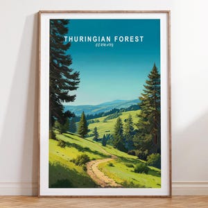May include: A framed art print featuring a scenic landscape of the Thuringian Forest in Germany. The artwork depicts a winding path through green hills and trees under a blue sky. The text "THURINGIAN FOREST GERMANY" is displayed at the top.