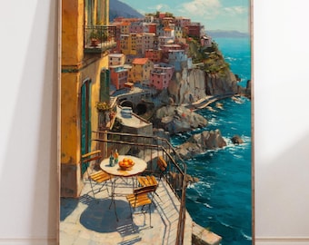 May include: A framed print of a coastal Italian village. The artwork depicts colorful buildings perched on a cliff overlooking the turquoise sea. A balcony with a table and chairs is in the foreground. The print is in a wooden frame.