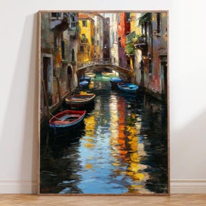 Peut inclure: Peinture à l'huile encadrée représentant une scène de canal vénitien. Des bâtiments colorés bordent le cours d'eau, avec un pont en arc. Plusieurs petits bateaux sont amarrés dans l'eau, reflétant les couleurs vives des bâtiments et du ciel. L'œuvre est dans un cadre en bois.
